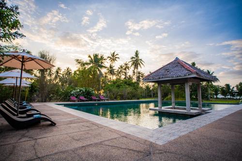 a swimming pool with a gazebo and chairs and an umbrella at Club Agutaya in San Vicente
