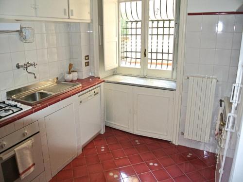 kuchnia z białymi szafkami i czerwoną podłogą wyłożoną kafelkami w obiekcie OS Garden - Maison de Charme w mieście Salerno