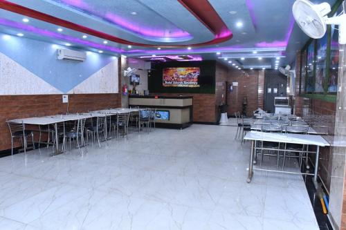 comedor con mesas y sillas y TV en Hotel Adarsh Residency Mangalam Group, en Haridwar
