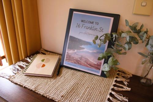 un marco de imagen sentado en una mesa junto a un libro en The Barn Cabins & Camp, en Marahau