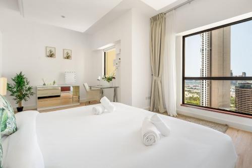 een slaapkamer met 2 witte bedden en een groot raam bij MAJESTIC JBR - SEA VIEW - Jumeirah Beach Residence in Dubai