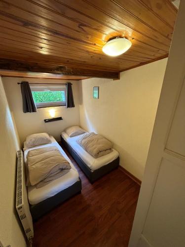 - 2 lits dans une petite chambre avec plafond dans l'établissement Camping du Château, à Granges-sur-Vologne