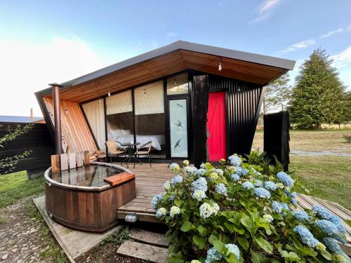 Casa pequeña con terraza de madera y bañera. en Mini Cabaña con Tinaja en Máfil