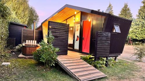 uma pequena casa com uma porta vermelha e um deque em Mini Cabaña con Tinaja em Máfil