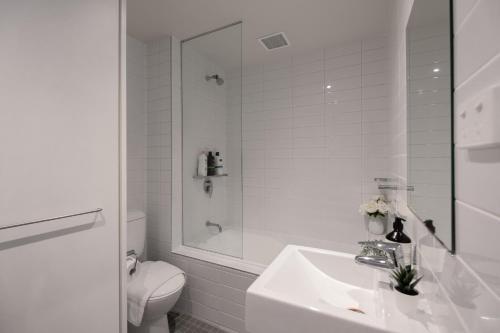 een witte badkamer met een wastafel en een toilet bij Generous 2br2ba Docklands Free Parkingpool in Melbourne