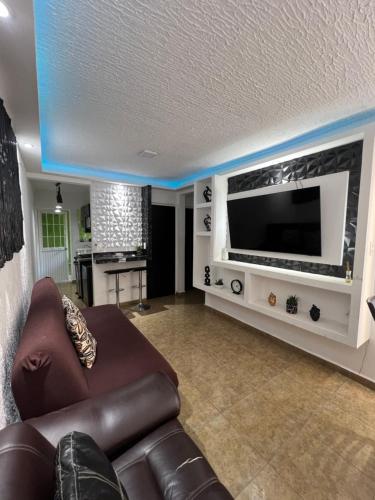 a living room with a couch and a large television at Departamento en Acapulco Diamante planta baja in La Sabana