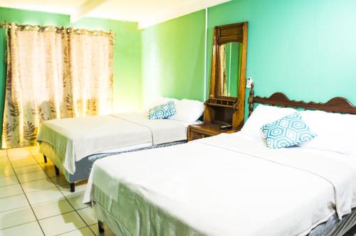 a bedroom with two beds and a mirror in it at Casa Lucia in Managua