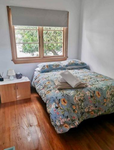 a bedroom with a bed and a window at Art Deco Charm - Amazing River Views Inner City in Gisborne