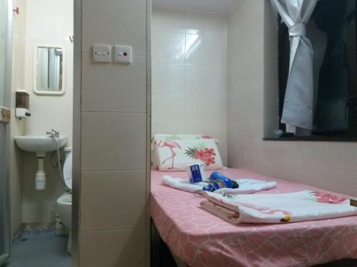 La salle de bains est pourvue d'une table rose, de serviettes et de toilettes. dans l'établissement NEW WASHINGTON GUEST HOUSE B1,B2 B LOCK 13 FLOOR CHUNG KING MANSHION, 36-44 NATHAN ROAD KOWLOON HONG KONG, à Hong Kong