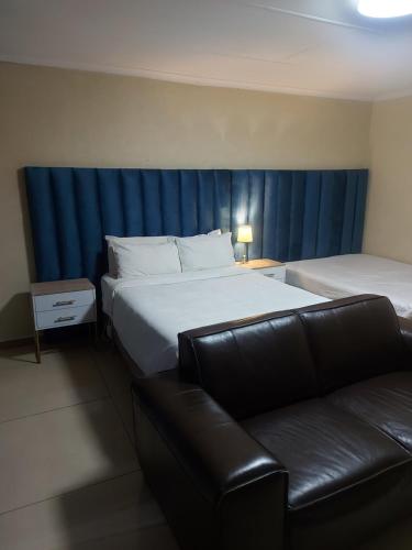 a hotel room with two beds and a couch at Purple Olive Guest House in Pretoria