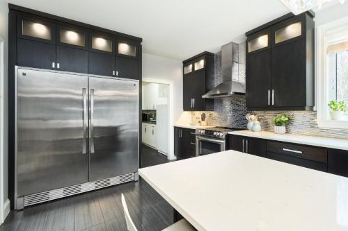 a kitchen with black cabinets and a stainless steel refrigerator at Luxury Forest Oasis 4 beds 4 baths and Hot tub in Cocagne 