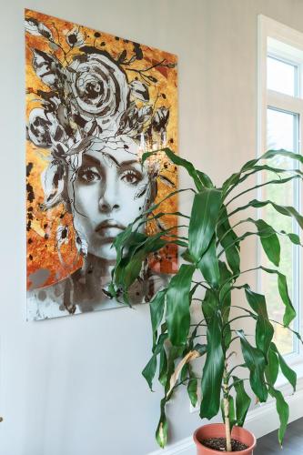 a plant in front of a painting of a woman at Luxury Forest Oasis 4 beds 4 baths and Hot tub in Cocagne 