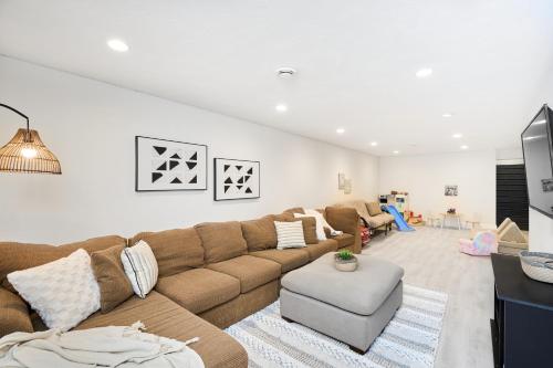 a living room with a brown couch and a tv at Luxury Forest Oasis 4 beds 4 baths and Hot tub in Cocagne 