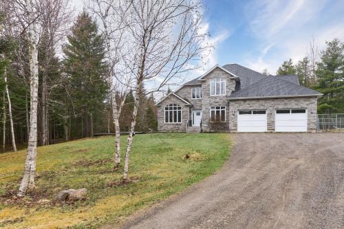 a house on a hill with a dirt road at Luxury Forest Oasis 4 beds 4 baths and Hot tub in Cocagne 