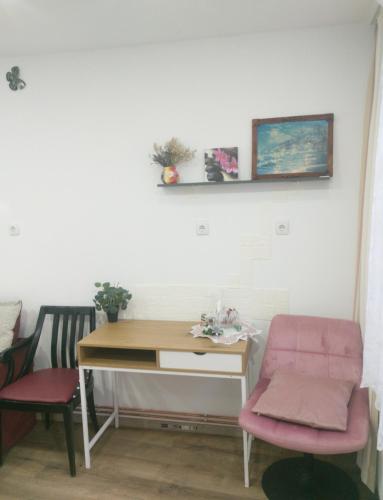 a desk and a chair in a room with a table and a pink chair at Reteganu Apartment in Dej