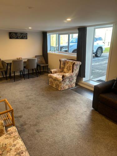 een woonkamer met een bank, stoelen en een tafel bij Team Mac Homestay in Rotorua
