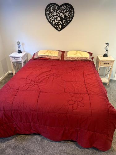 een slaapkamer met een rood bed en 2 nachtkastjes bij Team Mac Homestay in Rotorua