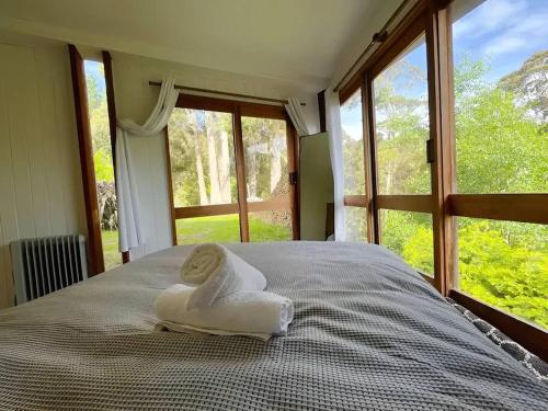 ein Bett mit einem Handtuch vor dem Fenster in der Unterkunft Wilderness Retreat 10mins to CBD, bath tub, BBQ in Ridgeway