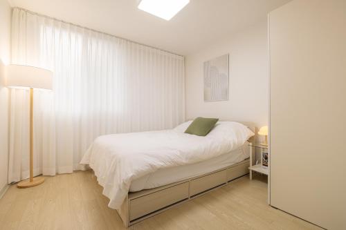 a white bedroom with a bed and a mirror at 이수환상 in Seoul