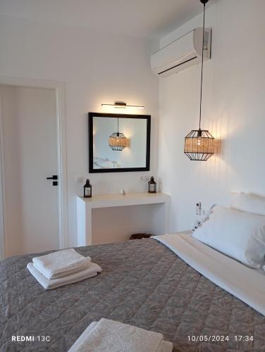 a white bedroom with a bed and a mirror at Sea melody tinos 3 in Agios Sostis