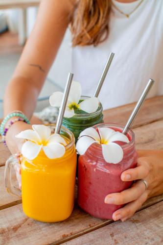 a woman sitting at a table with two jars of drinks at Orion Healing Centre in Srithanu