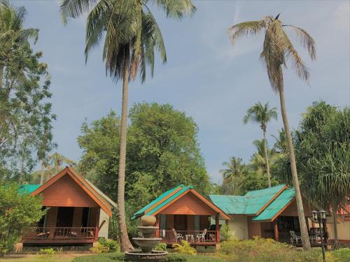 une maison avec des palmiers devant elle dans l'établissement Sayang Beach Resort Koh Lanta, à Ko Lanta