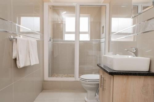 Bayside Hotel 14 Monty Naicker(Pinestreet) في ديربان: حمام ابيض مع مرحاض ومغسلة