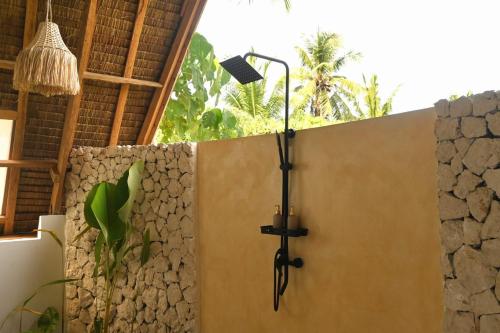 een douche met een licht aan de muur bij Pretty Jungle Siargao in San Isidro