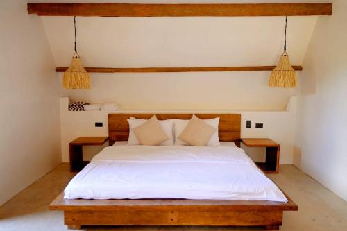 a bedroom with a bed with white sheets and pillows at Pretty Jungle Siargao in San Isidro