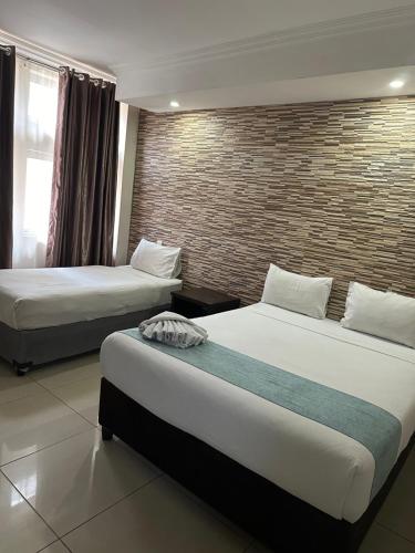 a hotel room with two beds and a brick wall at Bayside Self Catering and Hotel 14 Monty Naicker Pinestreet Durban in Durban