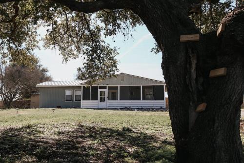 a house with a tree in front of it at Hadley's House - A Country 3 Bdrm with Screened-In Porch in New Braunfels