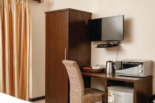Bayside Hotel 14 Monty Naicker(Pinestreet) في ديربان: غرفة بها مكتب مع تلفزيون وكرسي