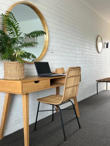 a desk with a laptop and a mirror at Mollymook Seascape Motel and Apartments in Mollymook