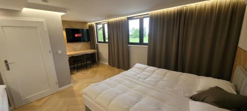 a bedroom with a white bed in a room with windows at Hotel & Restauracja Wróblewscy in Karniewo