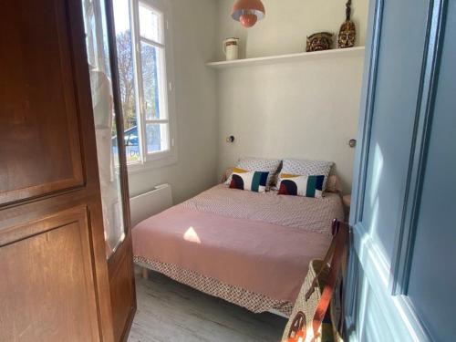 ein kleines Schlafzimmer mit einem Bett und einem Fenster in der Unterkunft Cabanon bohème les pieds dans le sable et en première ligne de mer in Marseillan
