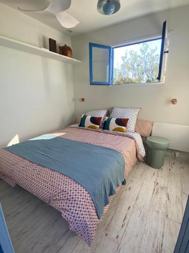 une chambre avec un lit et une fenêtre dans l'établissement Cabanon bohème les pieds dans le sable et en première ligne de mer, à Marseillan