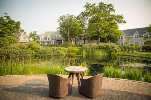 a table and chairs next to a pond with houses at Hôtel Le Bonne Entente in Quebec City