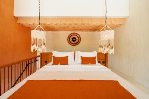 ein Schlafzimmer mit einem Bett mit orangefarbenen und weißen Kissen in der Unterkunft Cyrus Villa Seminyak by Ini Vie Hospitality in Seminyak