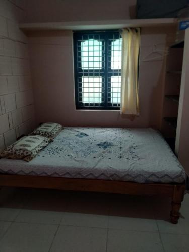 a small bed in a room with a window at SHARADHA NIVAS in Sringeri