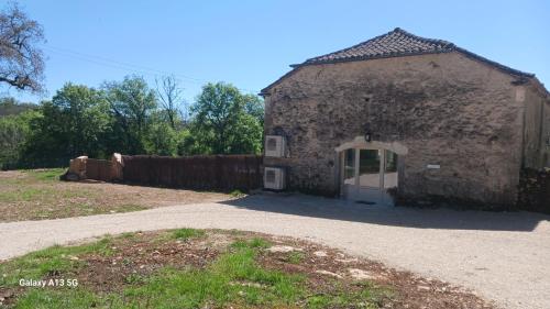 Crégols的住宿－Domaine de Bach，一座老石头建筑,在院子里有一扇门