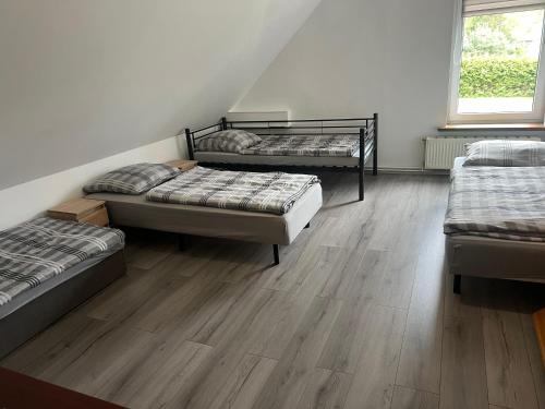 a room with three beds and a wooden floor at Pokoje na wsi in Bukowina