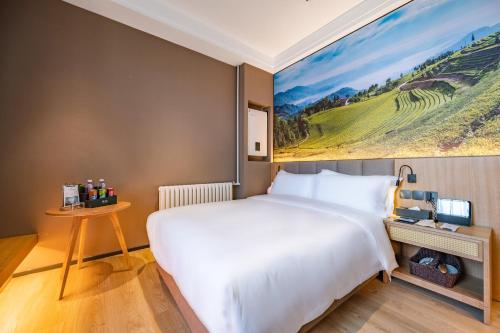 um quarto com uma cama grande e um quadro na parede em Qiuguo Hotel - Beijing Chaoyang Branch em Pequim