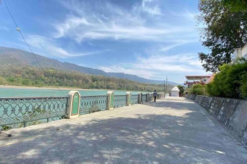 a person walking on a bridge next to a body of water at Beautiful Ganga side villa in Rishīkesh