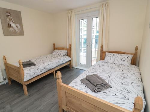 2 camas individuales en una habitación con ventana en Sunshine Cottage en Morpeth
