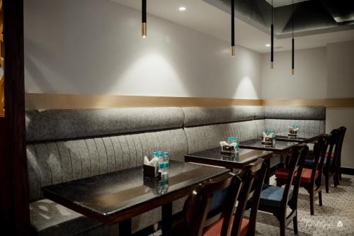 a dining room with two tables and a bench at Belvedere Suites in Greater Noida