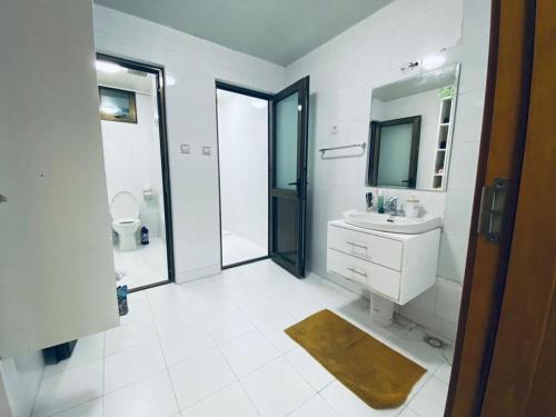 a white bathroom with a sink and a mirror at Appartement Meublé haut standing in Brazzaville