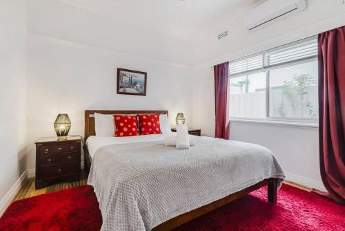 une chambre avec un lit avec des oreillers rouges et une fenêtre dans l'établissement Yarraville Garden Large home with yard and parking, à Yarraville