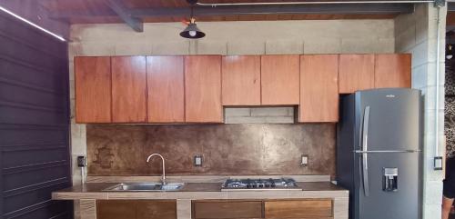 a kitchen with wooden cabinets and a stainless steel refrigerator at Casa Tapanco Tepoztlán in Tepoztlán