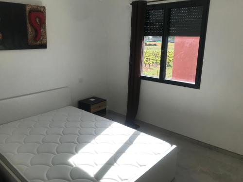 un lit dans une chambre avec une fenêtre dans l'établissement Villa 110 m2 entre vignoble et mer, à Marseillan