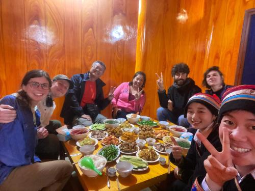 Un gruppo di persone seduti intorno a un tavolo che mangiano cibo di Homestay Trúc Sơn a Hong Ha